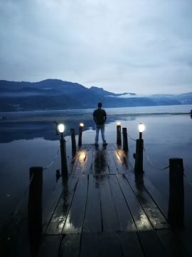 昏暗天空湖边码头上的男人背影