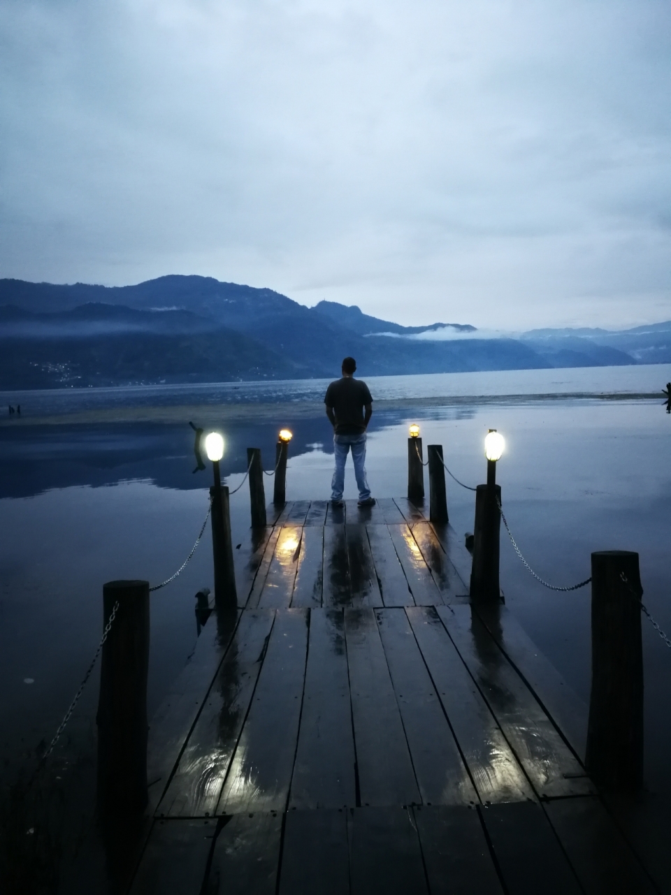 昏暗天空湖边码头上的男人背影