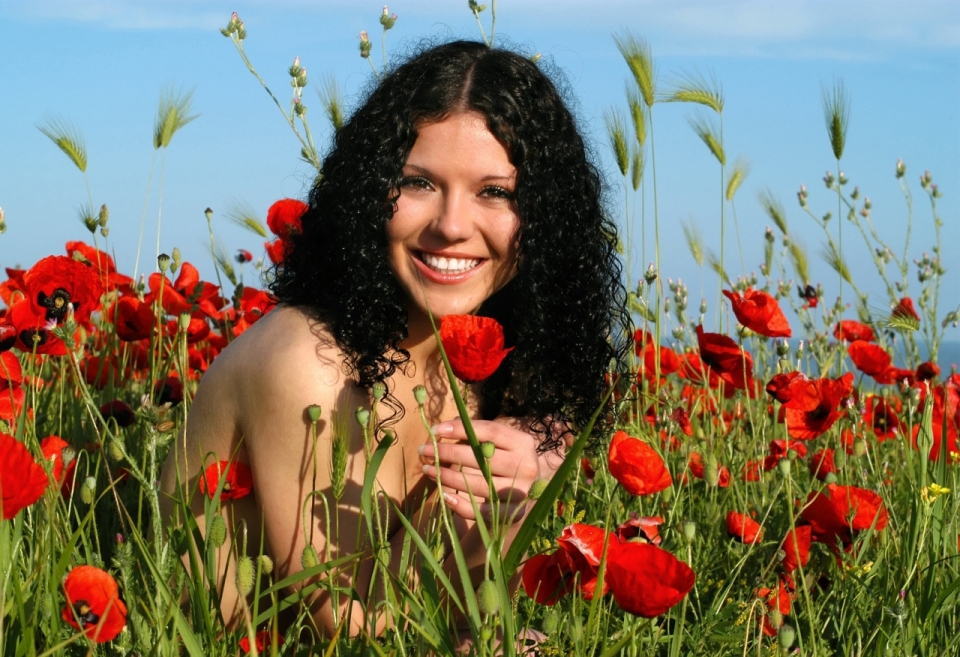 蓝色天空阳光红色花朵花丛间黑色卷发女性