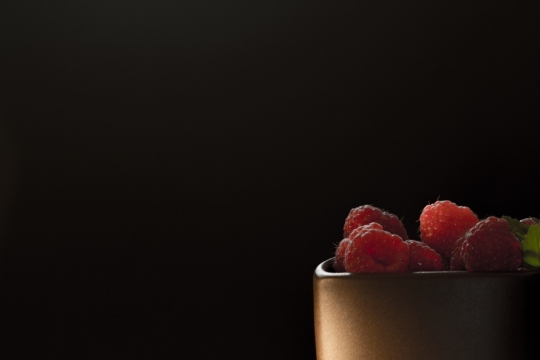 黑色背景金属容器中红色新鲜树莓果实