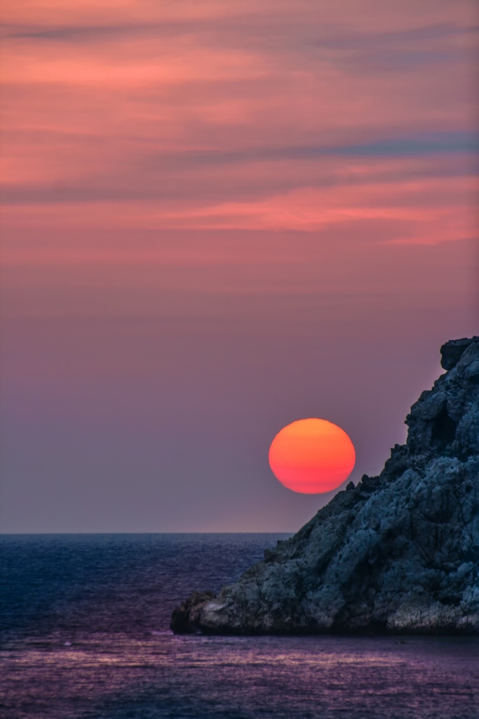 大海边悬崖落下火红色夕阳美景