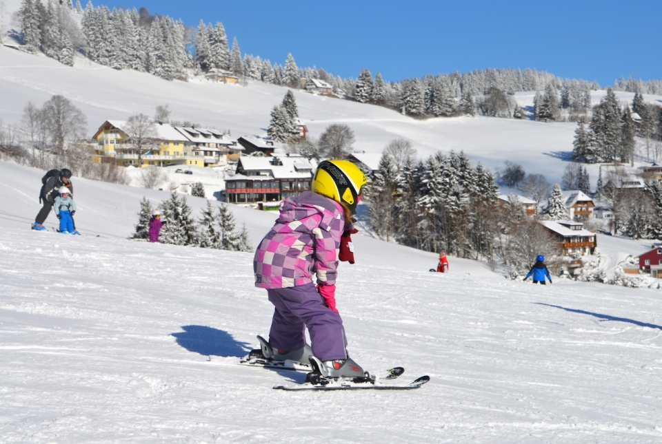 阳光下寒冷滑雪场戴黄色头盔滑雪运动儿童