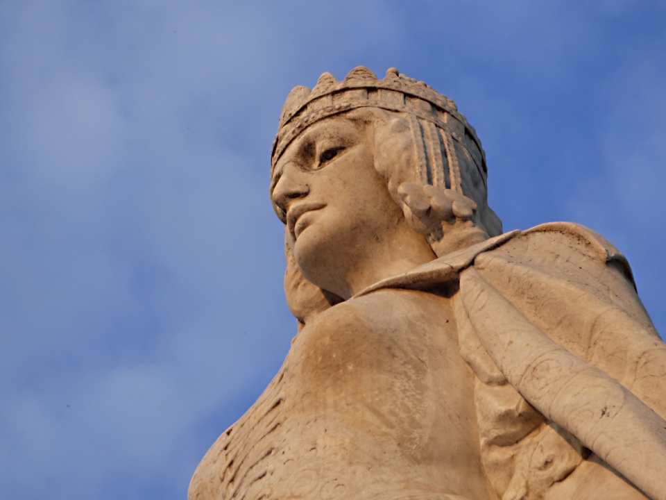 蓝色天空阳光下女性石质古老雕塑仰拍