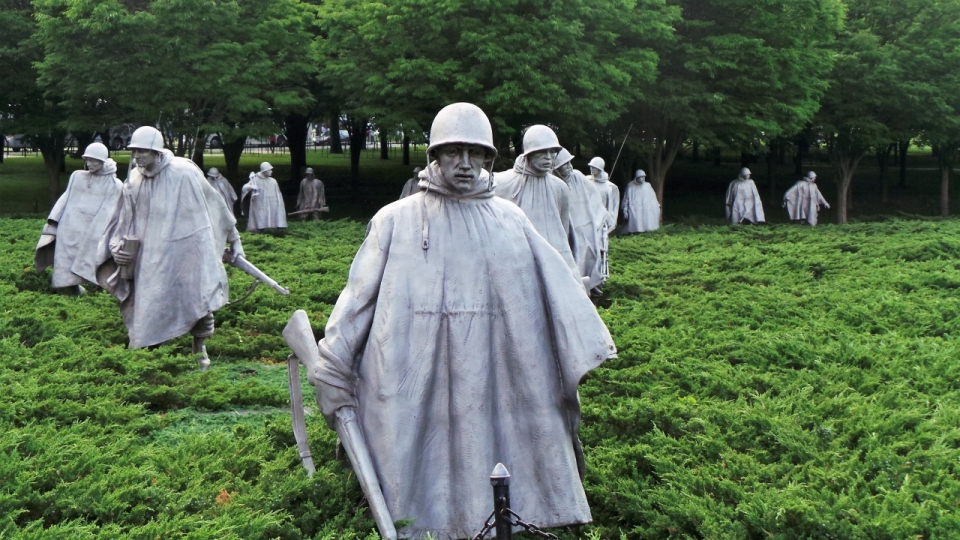 公园草丛中穿着雨衣的二战士兵雕像