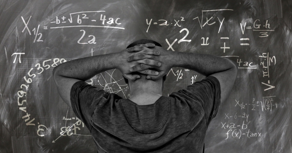 写满数学公式的黑板前的抱头男子