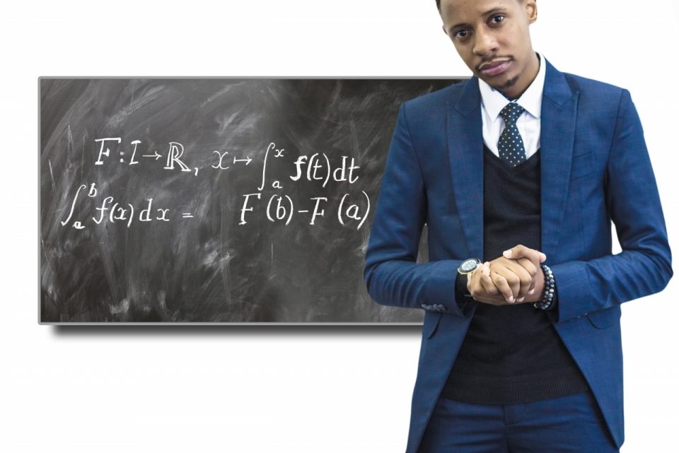 蓝色西装男子站在数学公式黑板前双手紧握