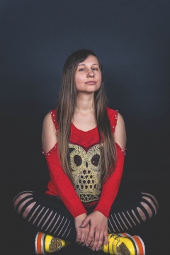 黑色背景前红衣女性盘腿休息