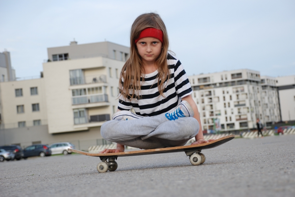 坐城市街道木制滑板上可爱长发女孩