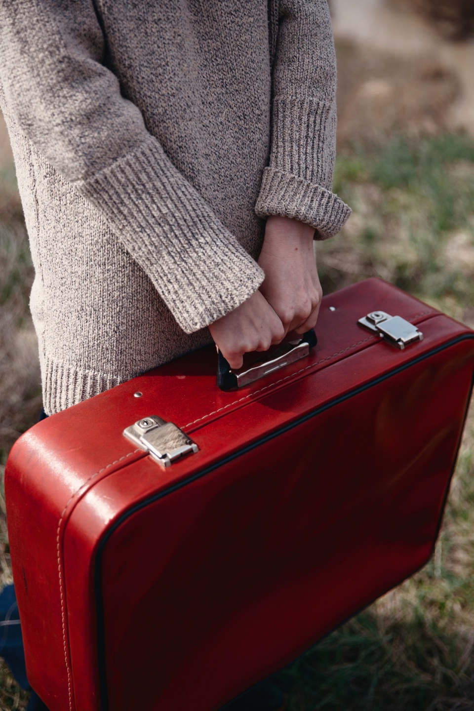 户外拎红色皮质行李箱女性手部特写