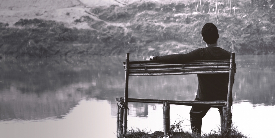 山下湖泊旁孤坐木凳上的人