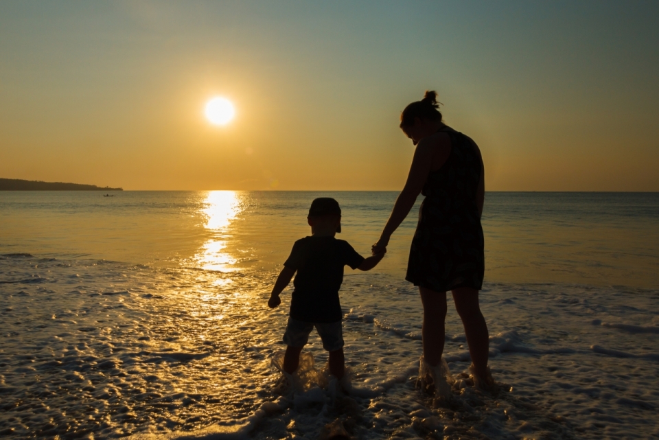 夕阳落日下海滩边水面上行走母子剪影摄影