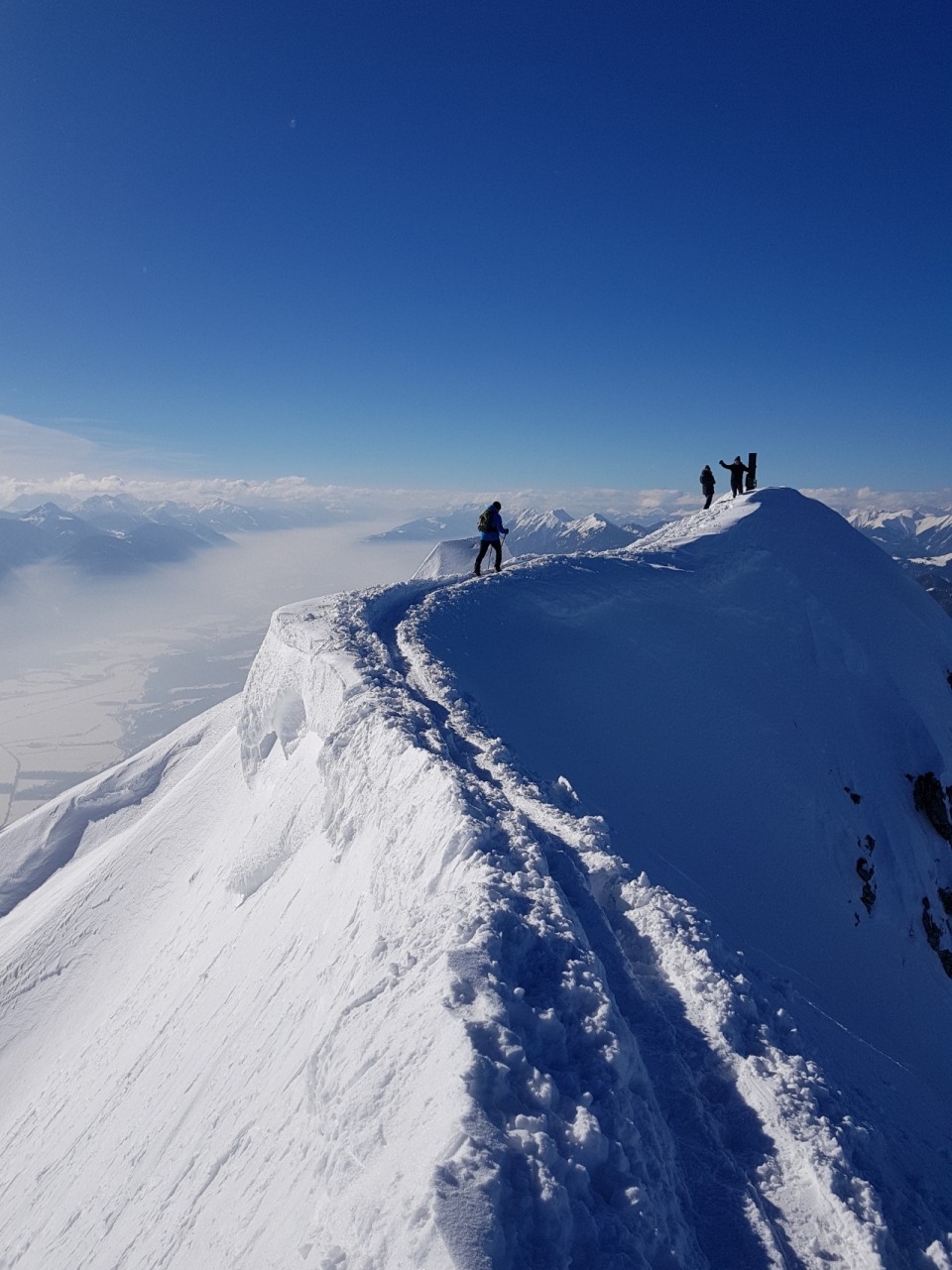 高耸洁白雪峰顶部行走的登山者