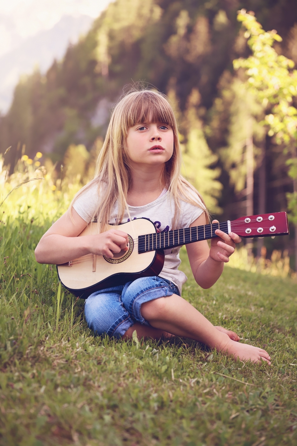欧美小女孩草坪上优美弹吉他摄影图片