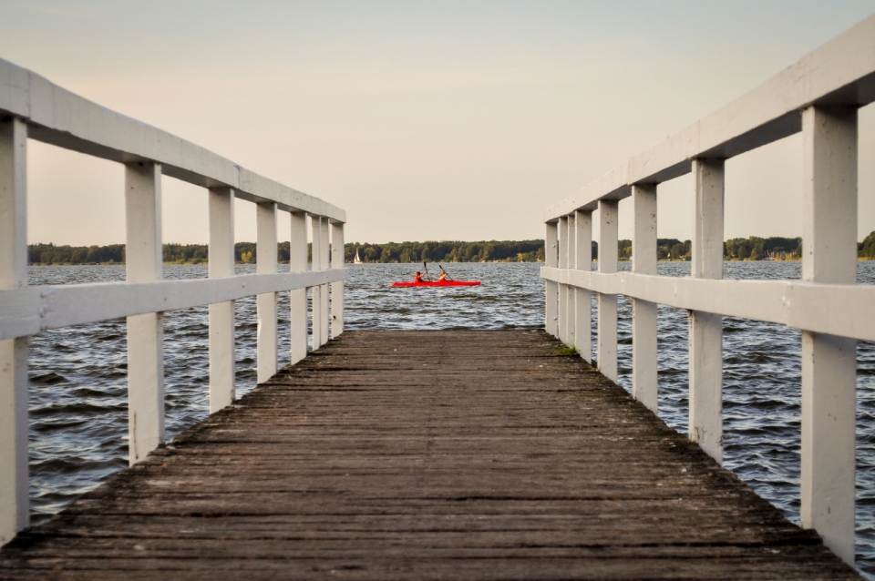 从木质栏杆小桥看湖畔湖面小船