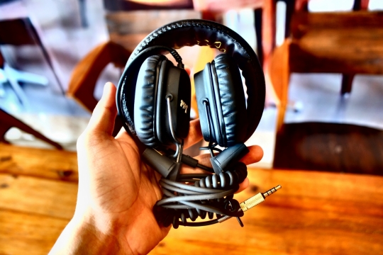 手拿盘起来的头戴式耳机和耳机线