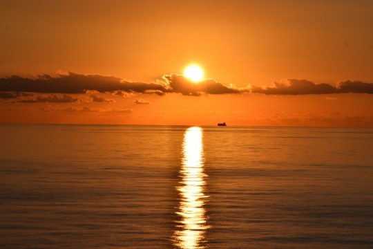 日落时分在广袤无垠的海面上留下长长倒影的太阳