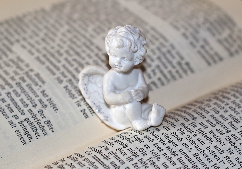 坐在书本上的白色小天使雕塑