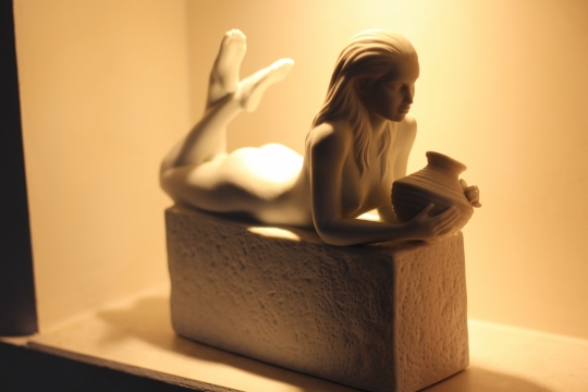 室内橙色灯光下白色石质美人鱼艺术雕像