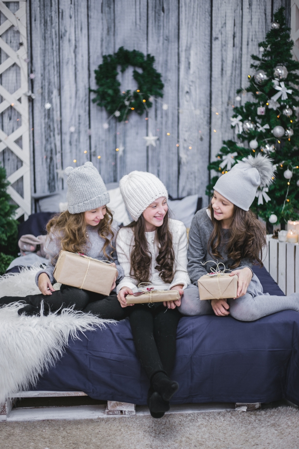 圣诞节木屋床上坐着拿到礼物的小女孩们