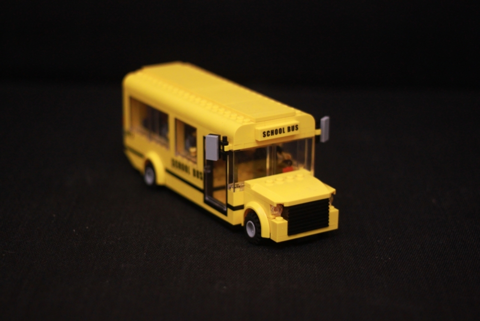简约黑色背景桌面上的黄色校车玩具模型