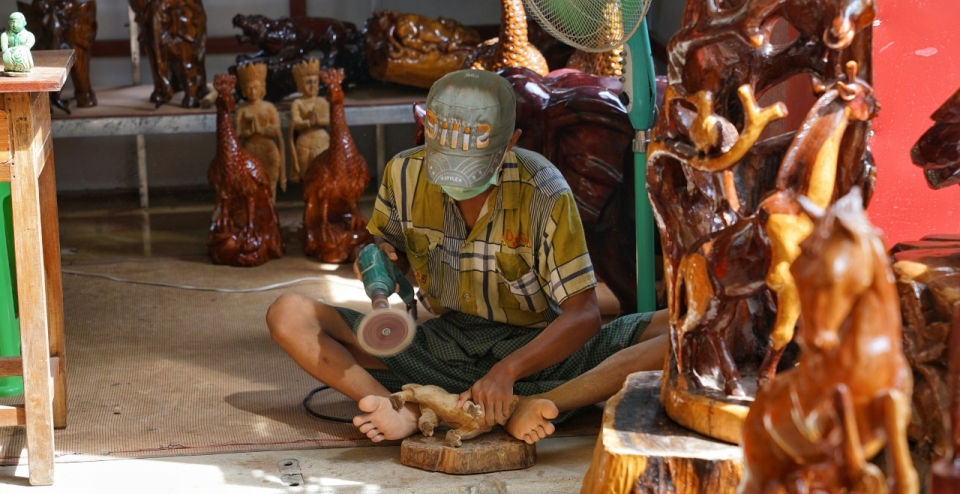 木雕店里坐在地上打磨木雕的店员