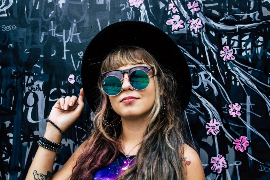彩绘墙壁前戴帽子墨镜时尚长发女性
