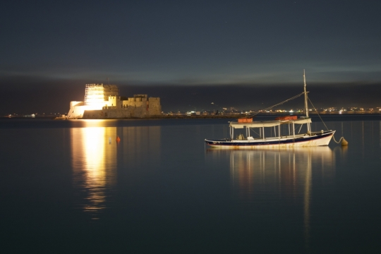 夜晚湖面停泊无人船只远处刺眼建筑灯光