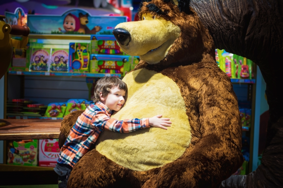 玩具商店中抱着巨大玩具熊的小男孩