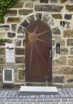 街边石墙上雕刻着太阳文耀的铁门