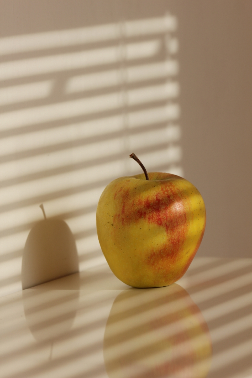 阳光透过百叶窗照在桌上的的苹果