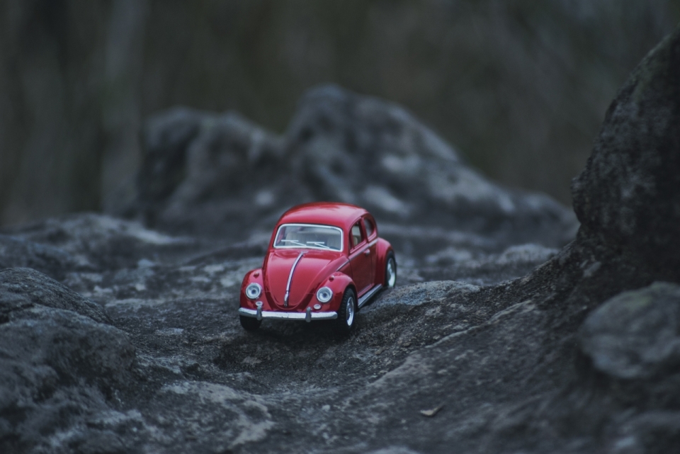 自然岩石间小巧红色崭新轿车模型