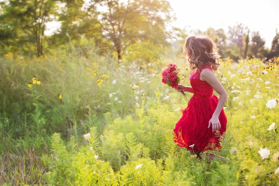 跳跃在花草丛中的红色连衣裙小女孩