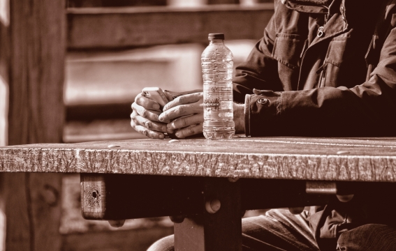 黄昏下坐在石桌前的男子与石桌上的水