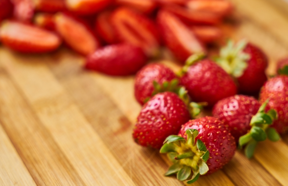 木质切菜板上红色草莓被切开水果美食