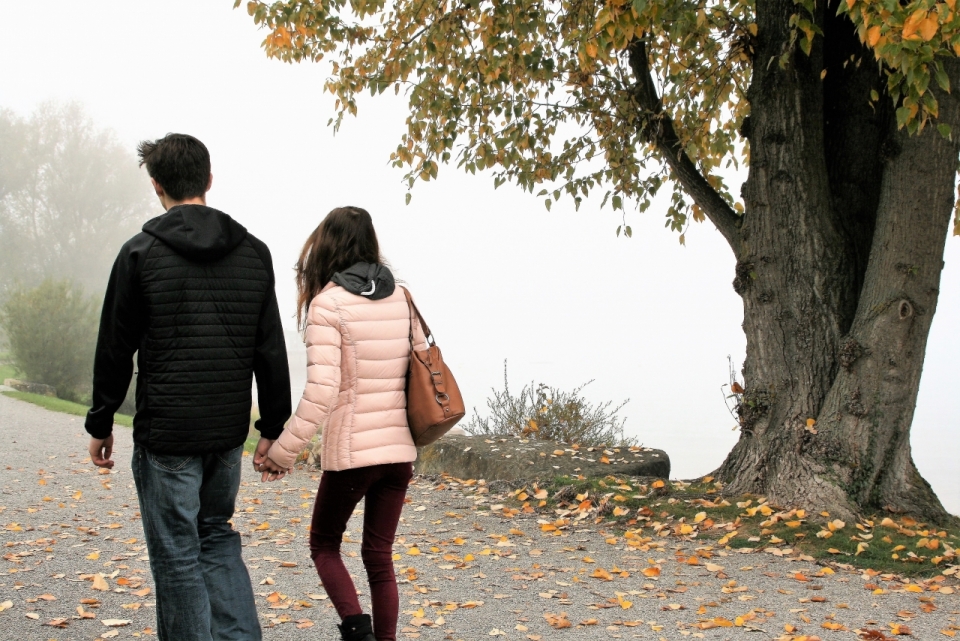 情侣在满是落叶的道路上散步