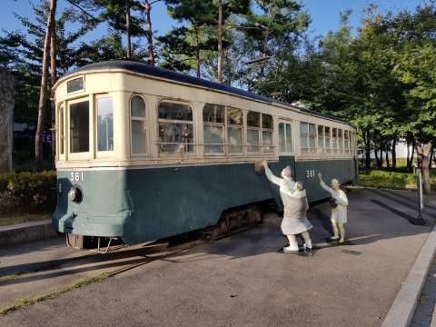 被城市中树木环绕的列车与送行女性雕塑