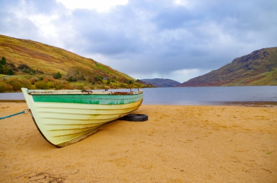 宽广湖泊的沙滩上老旧搁浅的小船