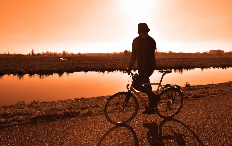 夕阳下湖边小路骑自行车的人
