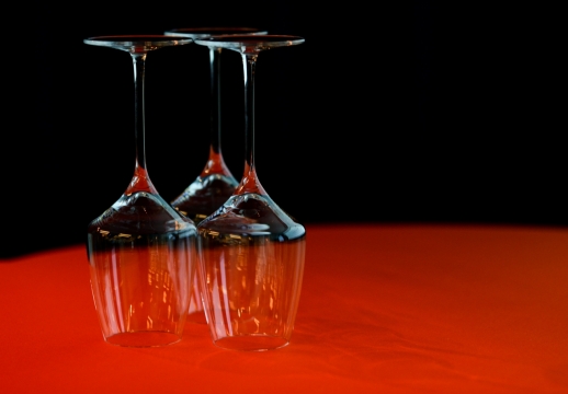 黑色背景红色桌面上倒放酒杯