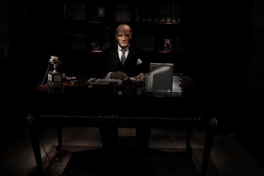 黑暗建筑室内办公桌前秃头西装男性