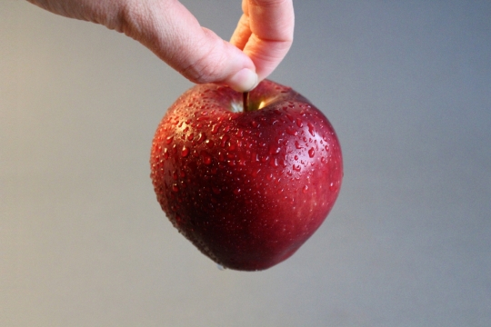 手拿新鲜健康美味沾水红色苹果