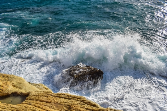 站立海边山顶俯瞰翻滚海浪白色水花自然风光