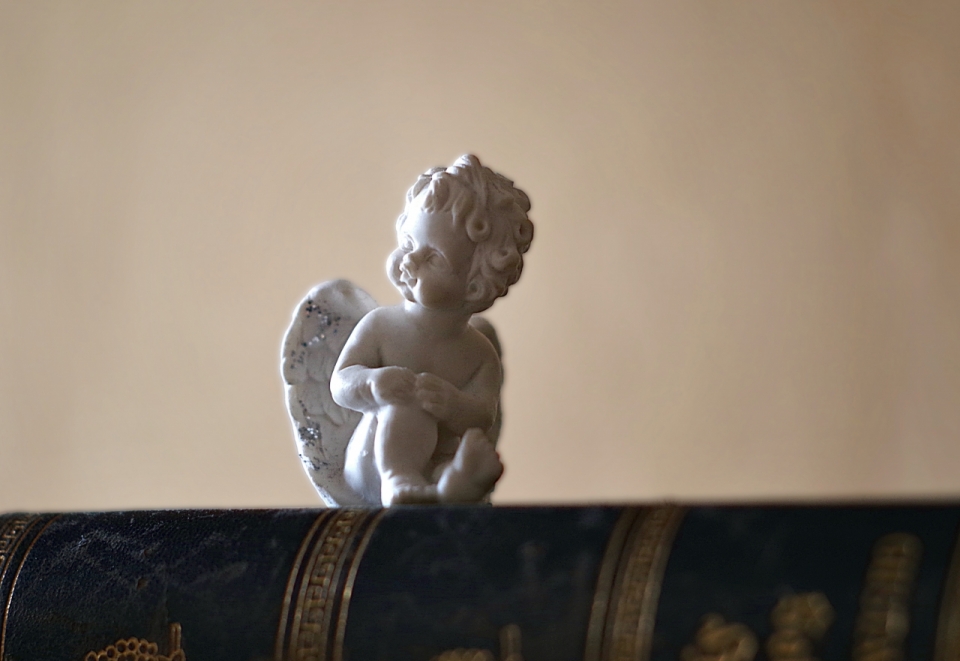 在黑色桌上的白色小天使雕像静物摄影