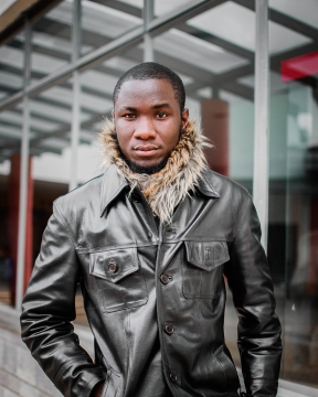 现代城市街道建筑边穿黑色皮衣时尚黑人男性