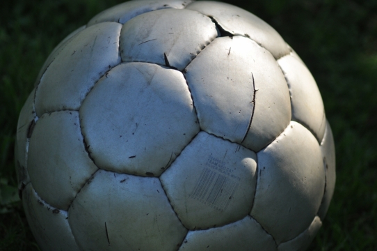 早地上破旧的银色足球静物摄影