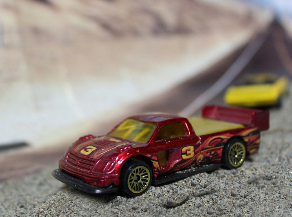 公路边岩石上红色黄色玩具汽车模型特写摄影