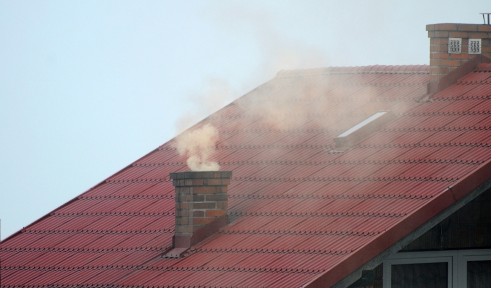 蓝色天空中红色屋顶烟囱冒黄色烟雾
