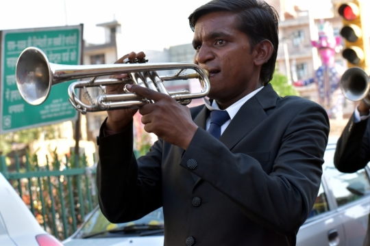 穿着西装正在街头吹奏小号的青年