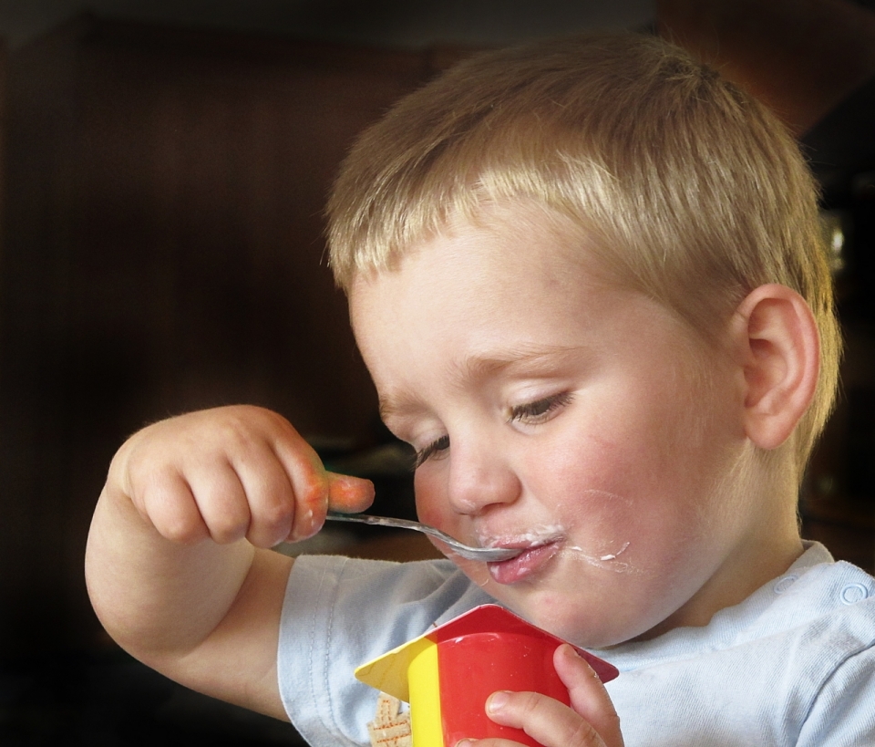 正拿着勺子吃酸奶的可爱男孩
