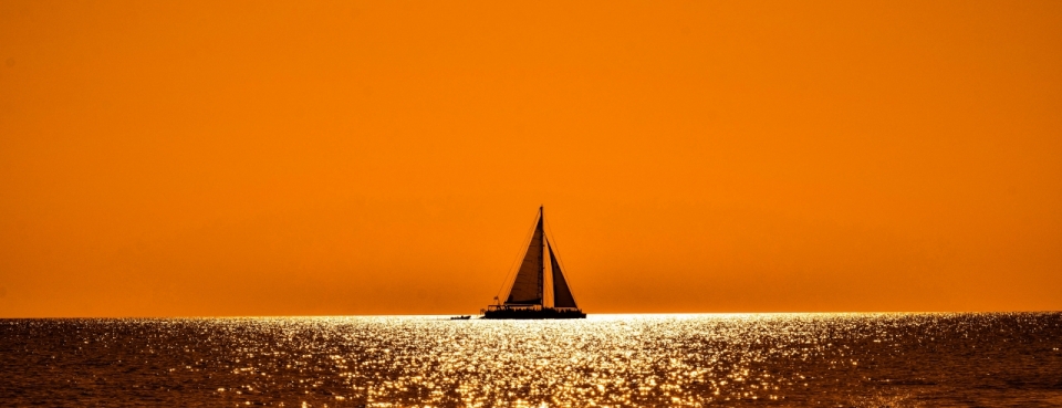 橙色天空金色海面上帆船摄影